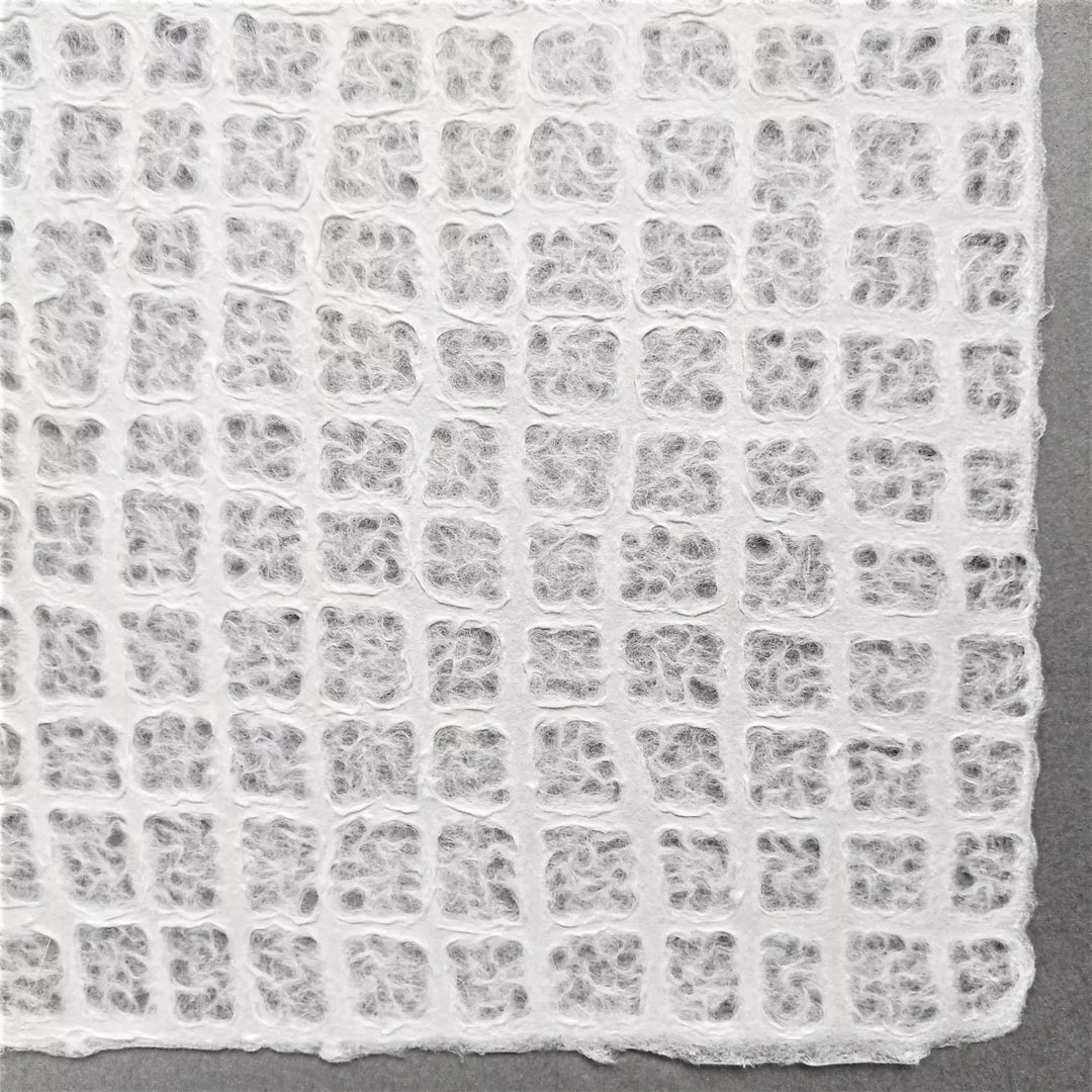 Waffle-textured handmade paper sheet from Kozo Studio created with mulberry fibers, offering both elegance and versatility for art or interior use.