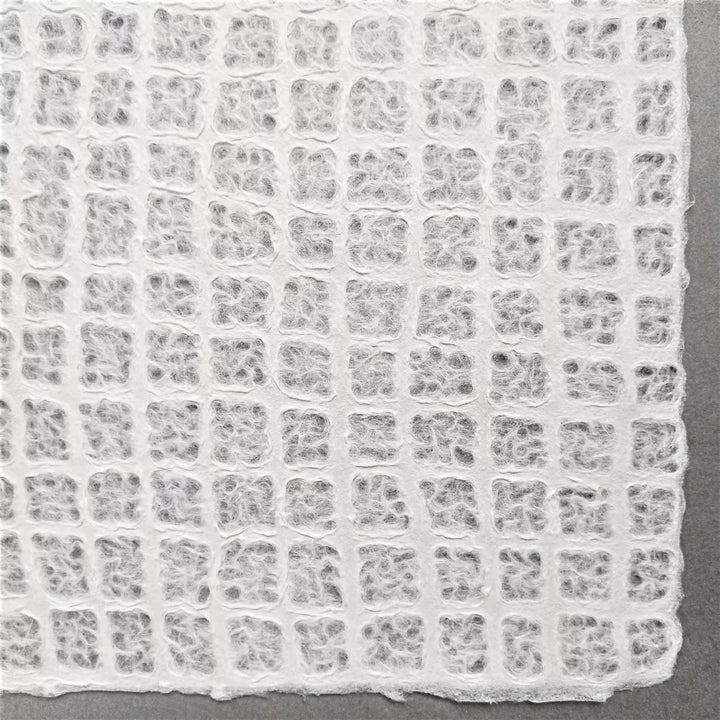 Waffle-textured handmade paper sheet from Kozo Studio created with mulberry fibers, offering both elegance and versatility for art or interior use.