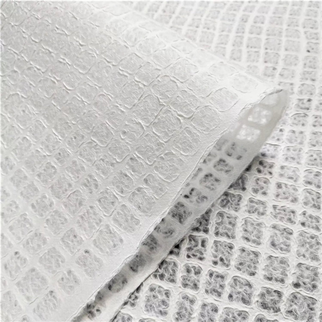 Translucent lace mulberry paper by Kozo Studio, photographed in close-up to reveal its intricate handmade waffle texture, used in fine craft and lighting design.