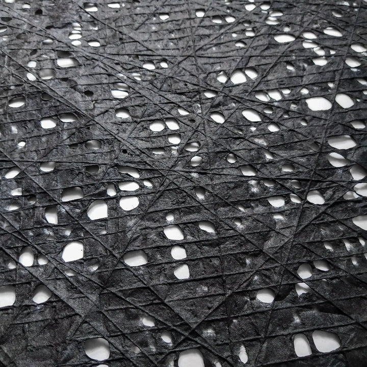 Handmade mulberry paper from Kozo Studio with a distinctive fishnet design in black, achieved through an artisanal process of layering cotton threads over kozo pulp.