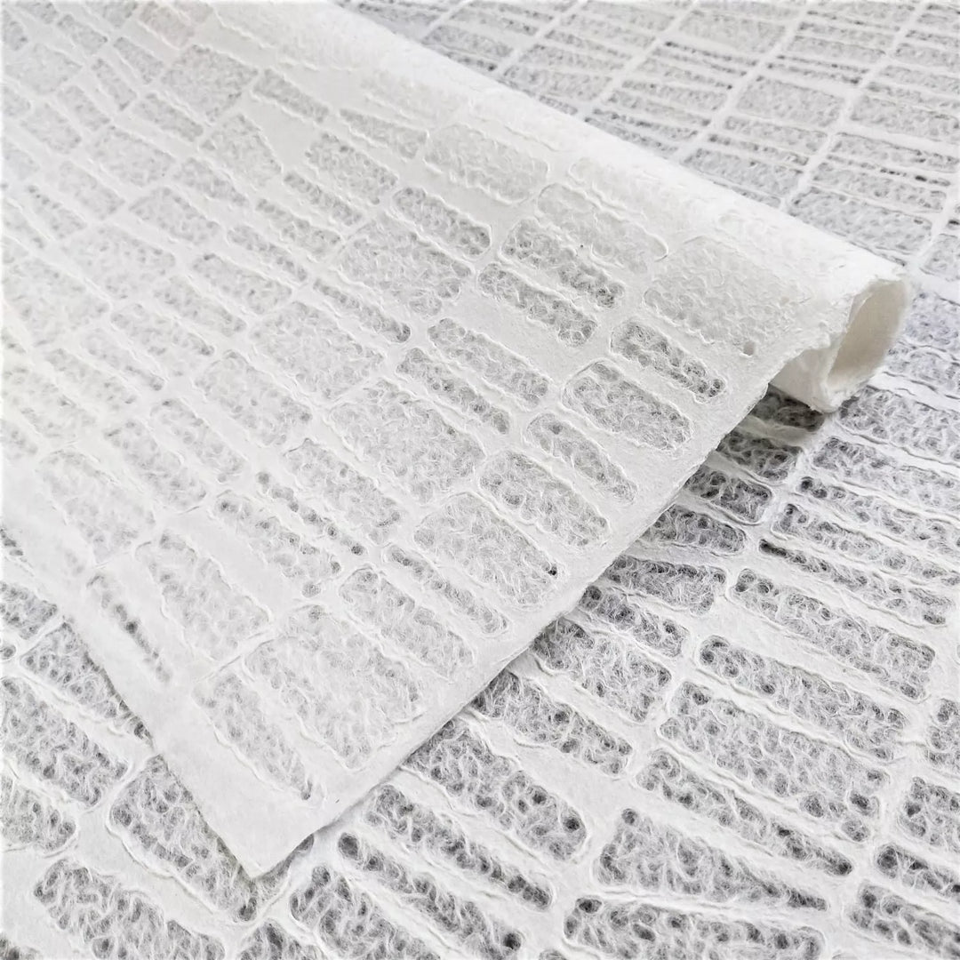 Close-up of handmade lace mulberry paper by Kozo Studio showcasing an Egyptian-inspired stone-brick pattern with textured white fibers and woven-style ridges.