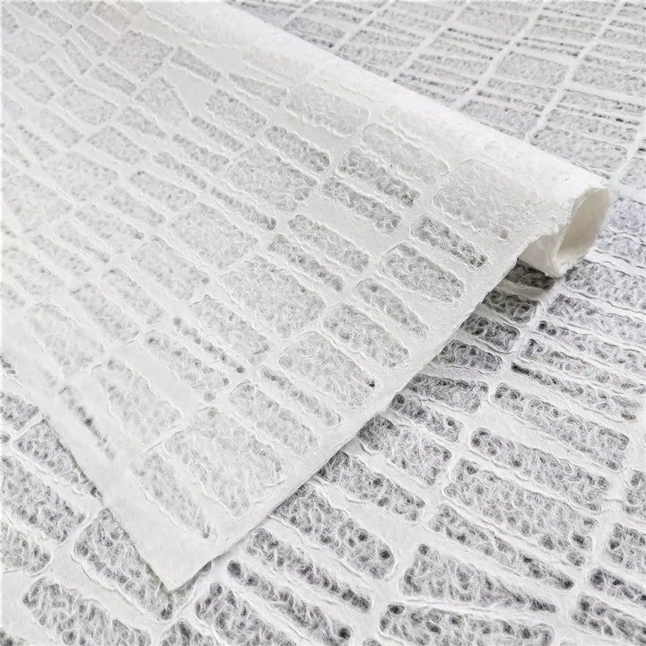 Close-up of handmade lace mulberry paper by Kozo Studio showcasing an Egyptian-inspired stone-brick pattern with textured white fibers and woven-style ridges.