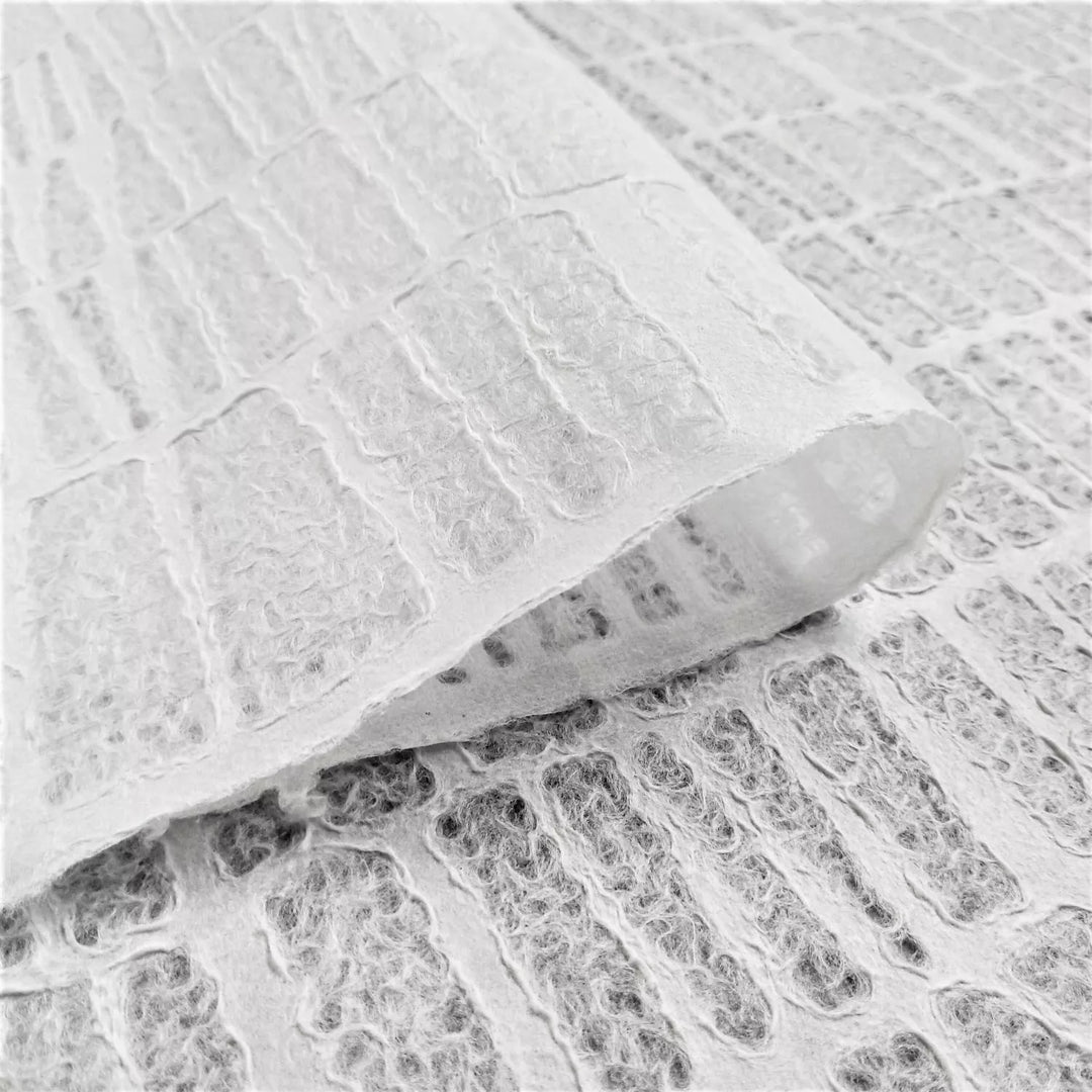 A close-up image of handmade paper by Kozo Studio, displaying lace-style mulberry paper with an Egyptian brick pattern and a woven texture from layered, fibrous sections.