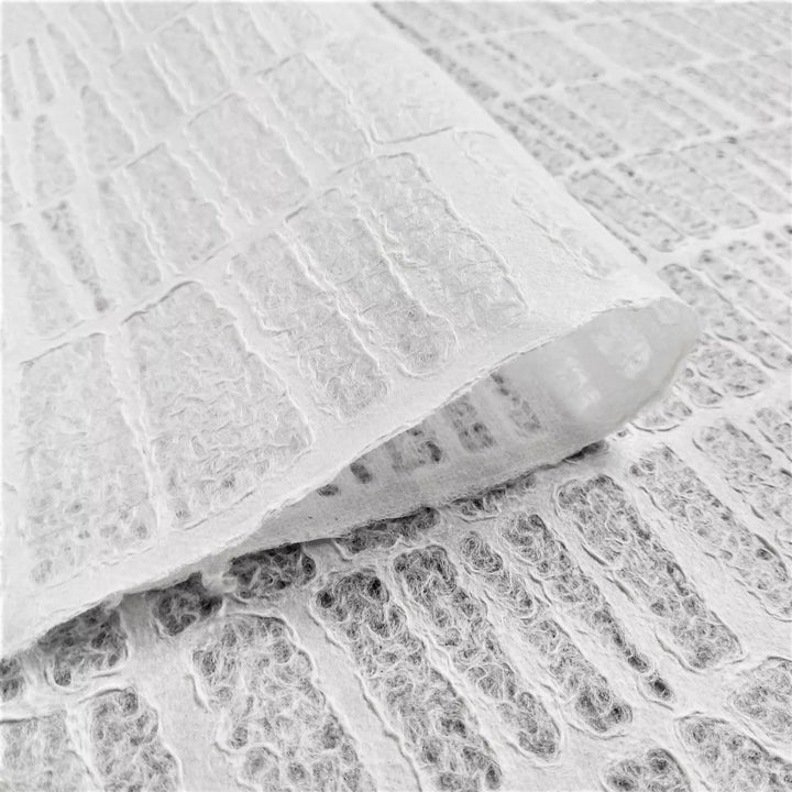 A close-up image of handmade paper by Kozo Studio, displaying lace-style mulberry paper with an Egyptian brick pattern and a woven texture from layered, fibrous sections.