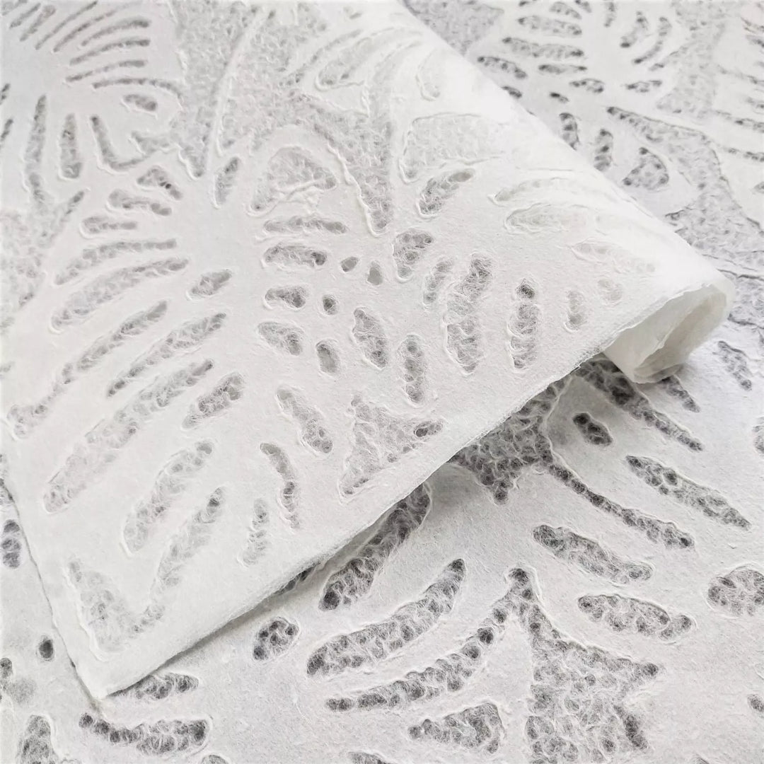 Close-up of white handmade mulberry paper from Kozo Studio featuring a delicate Monstera leaf design with translucent texture ideal for creative projects and lampshades.
