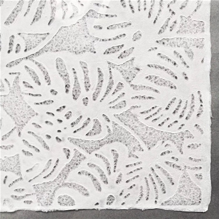 Detailed image of Kozo Studio handmade paper with Monstera-style lacework, rolled slightly to reveal the fine mulberry paper structure and its natural translucency.