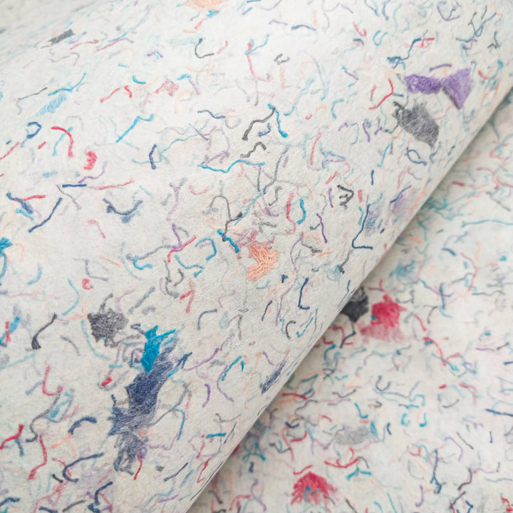 Handmade paper made with kozo pulp and embedded cotton bits from Kozo Studio, highlighting the colorful texture and artisanal quality of mulberry paper.