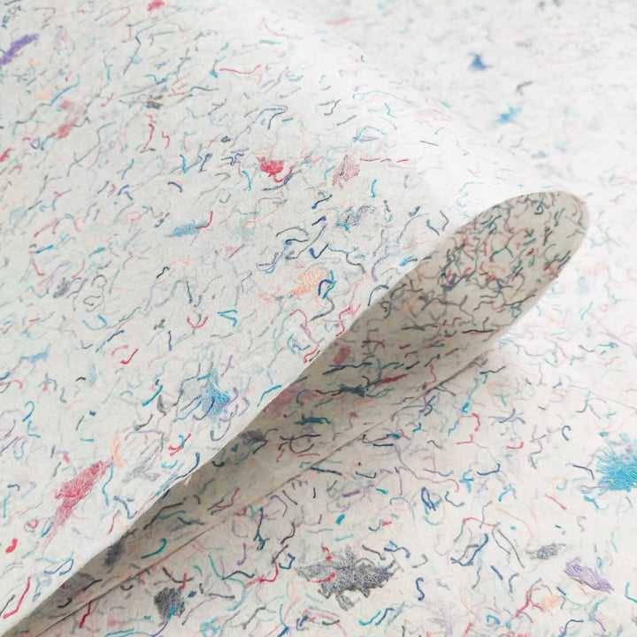 Close-up of Kozo Studio mulberry paper infused with chunks of colorful cotton, demonstrating its vibrant design and hand-crafted nature.