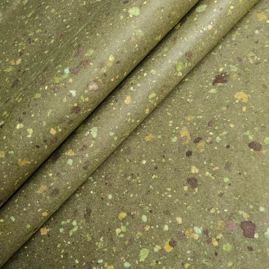 Artisanal mulberry paper sheet with visible specks of earthy bond paper on green-tinted kozo pulp, highlighting Kozo Studio's handmade paper expertise.