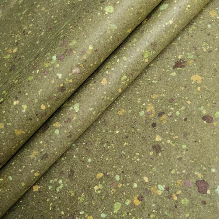 Artisanal mulberry paper sheet with visible specks of earthy bond paper on green-tinted kozo pulp, highlighting Kozo Studio's handmade paper expertise.