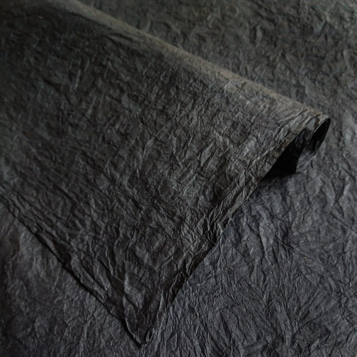 Artistic view of Kozo Studio's black Momigami paper, a handmade mulberry paper with a crumpled rice paper finish, perfect for bookbinding, wrapping, and decor.