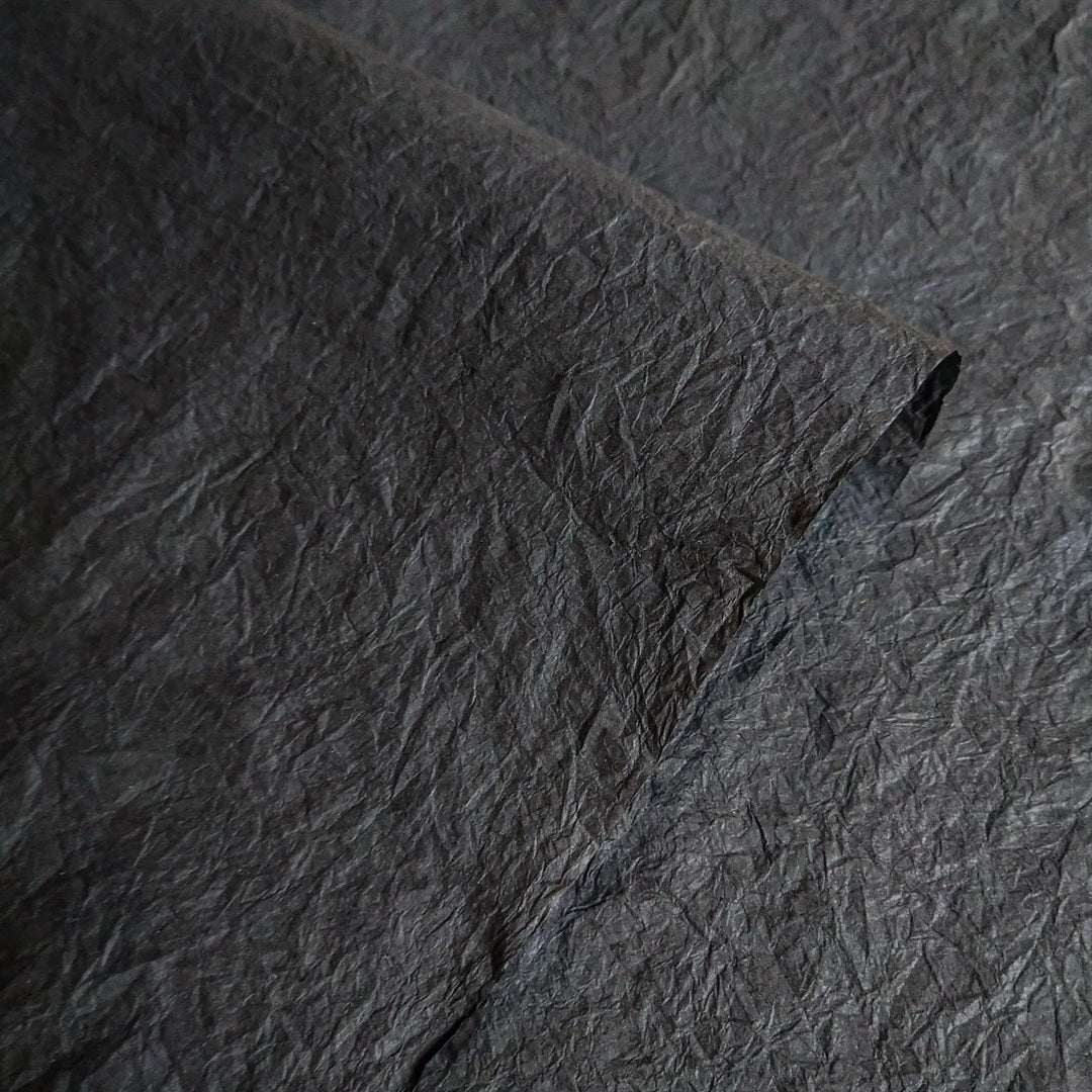 Close-up of black Momigami handmade paper from Kozo Studio, showcasing the crumpled texture and flexibility of premium mulberry paper ideal for arts and crafts.