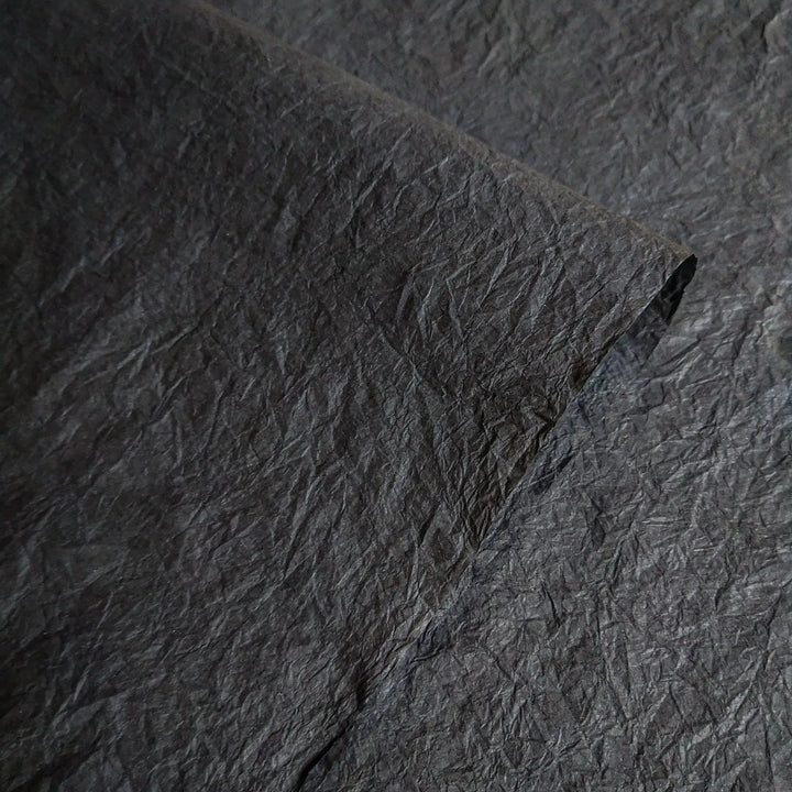 Close-up of black Momigami handmade paper from Kozo Studio, showcasing the crumpled texture and flexibility of premium mulberry paper ideal for arts and crafts.