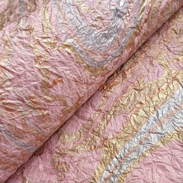 A close-up of Milano Kozo Paper - Design 15 (Pink) by Kozo Studio shows crumpled pink mulberry paper with metallic silver and gold swirls. The wrinkled and shiny surface forms an abstract pattern.