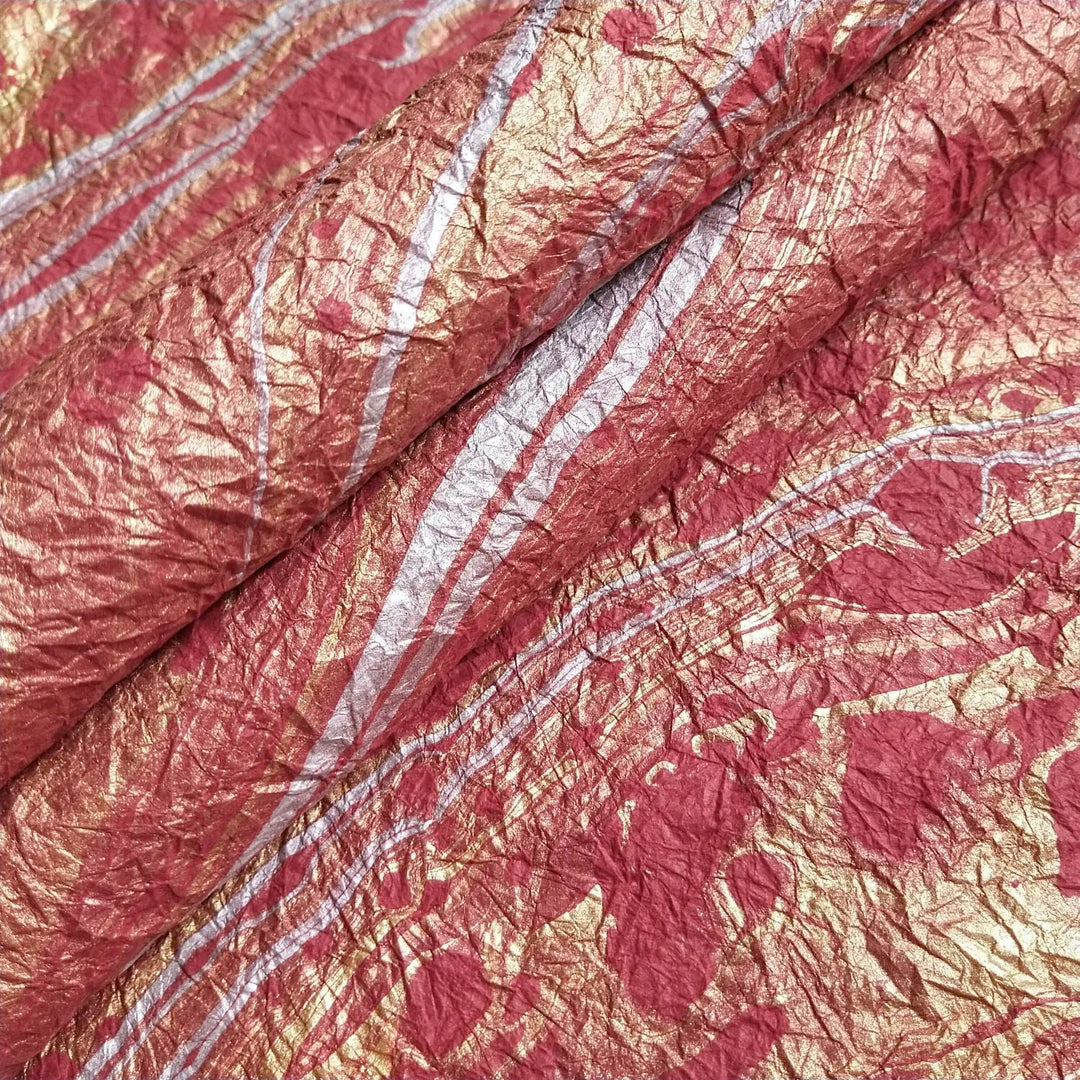 Hand-marbled red mulberry paper from Kozo Studio, featuring swirling oil-based patterns on soft handmade paper for artistic and decorative use.