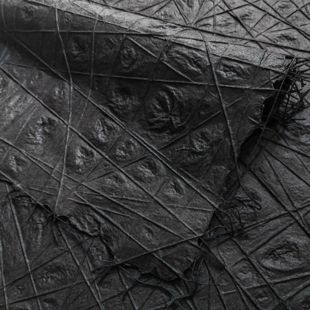 Black handmade paper from Kozo Studio featuring interlaced cotton threads embedded in premium mulberry paper, showcasing delicate water dimpling and intricate texture.