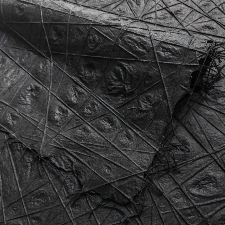 Black handmade paper from Kozo Studio featuring interlaced cotton threads embedded in premium mulberry paper, showcasing delicate water dimpling and intricate texture.