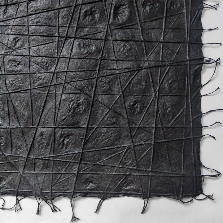 Intricately woven handmade paper from Kozo Studio, created from high-quality mulberry fibers and cotton threads laid in organic, interlaced patterns on a black background.