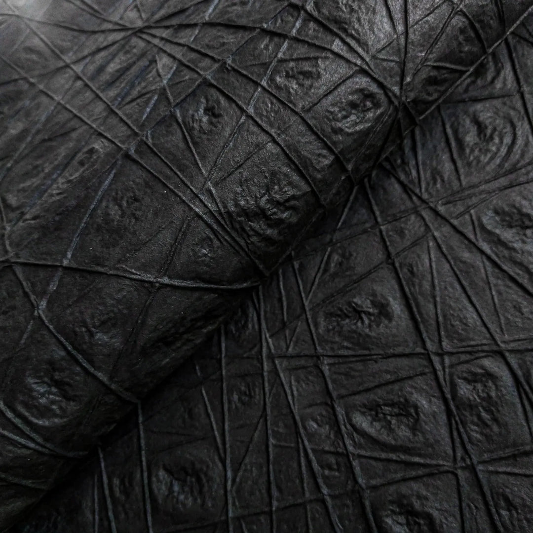Close-up of the Handmade Interlace Kozo Paper in black from Kozo Studio, featuring a leathery, diamond-patterned texture on mulberry paper with raised intersecting lines for a rugged and tactile appearance.
