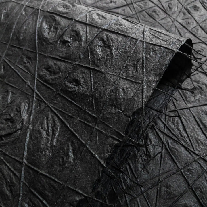 Detailed view of black mulberry paper handcrafted by Kozo Studio, featuring unique threadwork and subtle water dimpling that enhances its handmade texture and visual depth.