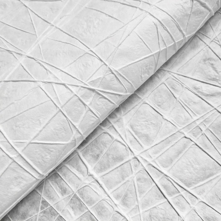 Close-up of Kozo Studio’s Handmade Interlace Kozo Paper (White) displaying its textured mulberry surface. The paper features an overlapping geometric design with intersecting lines and creases, forming a pattern of irregular shapes with varying texture and shadows.