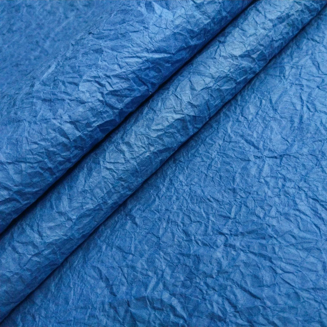 Crumpled blue Momigami handmade paper made from mulberry, created by Kozo Studio for artistic uses like paper bags, decor, and wrapping.