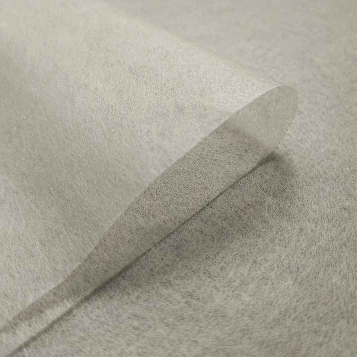 A close-up of Kozo Studio’s Conservator No.1 washi paper (8.5 gsm; 15 sheets/pack) highlights a single translucent sheet partially lifted, revealing its delicate texture and lightweight quality.
