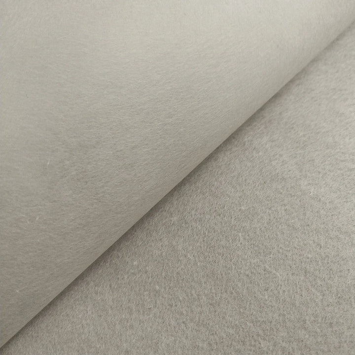 A close-up of Kozo Studio’s Conservator No.1 washi paper (8.5 gsm; 15 sheets/pack) shows a lifted edge, revealing subtle kozo fibers and a softly textured light gray surface.
