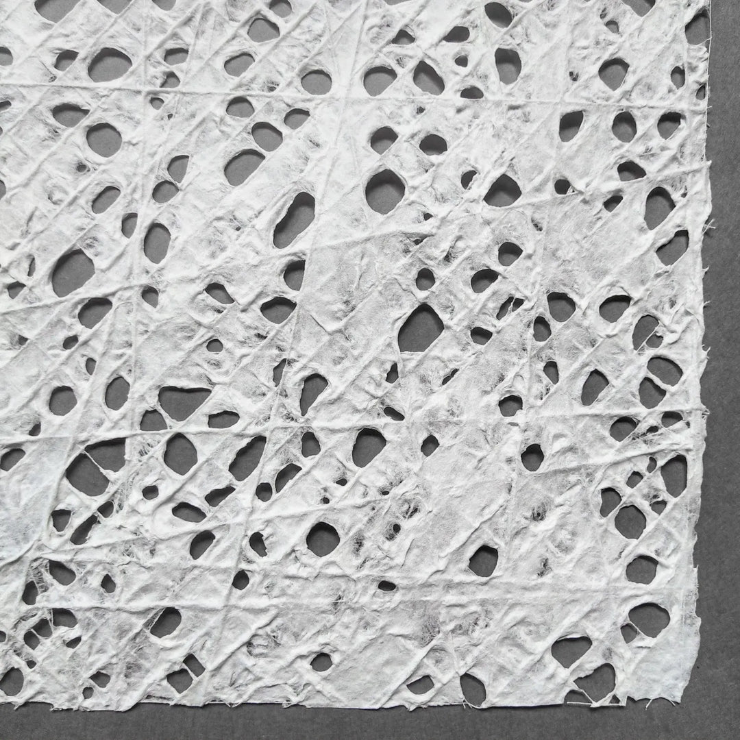 Kozo Studio handmade paper sheet featuring a unique fishnet pattern of cotton threads embedded in premium white mulberry pulp.