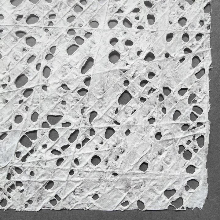 Kozo Studio handmade paper sheet featuring a unique fishnet pattern of cotton threads embedded in premium white mulberry pulp.