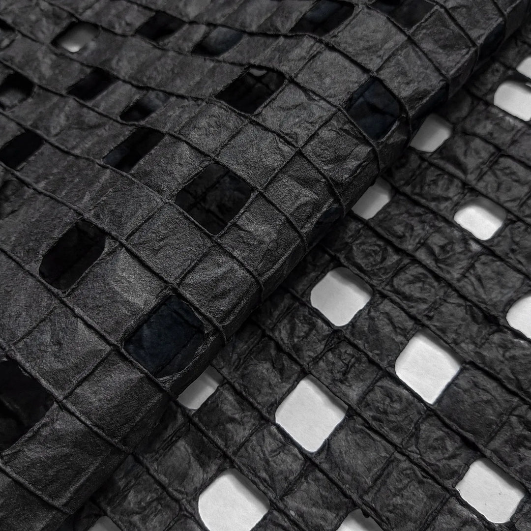 Artisan-made black mulberry paper by Kozo Studio with a unique hand-drawn grid pattern, ideal for creative projects.