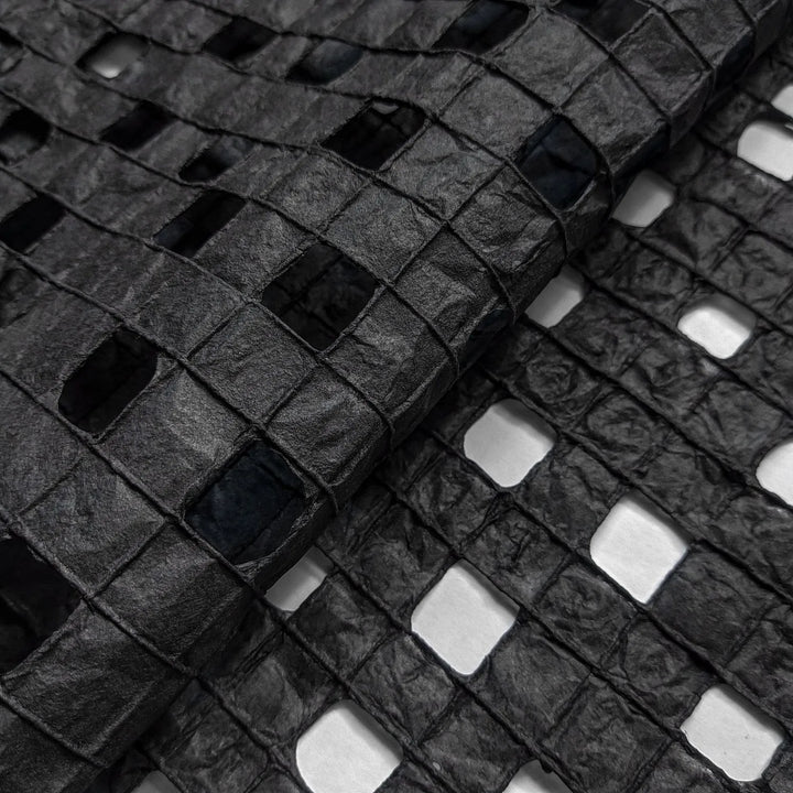 Artisan-made black mulberry paper by Kozo Studio with a unique hand-drawn grid pattern, ideal for creative projects.