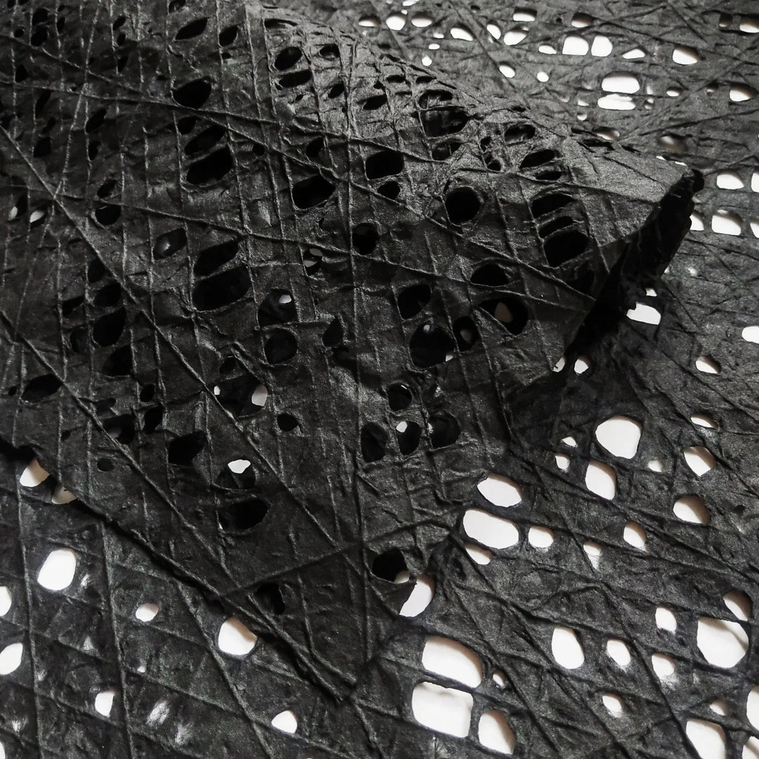 Intricately designed black mulberry paper with a hand-drawn fishnet pattern, meticulously crafted by Kozo Studio using kozo pulp and cotton threads.