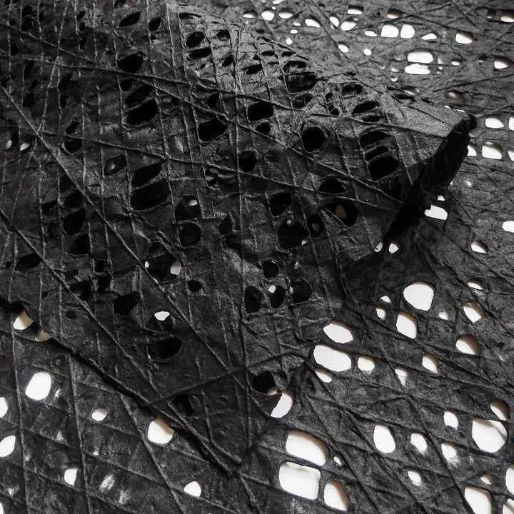 Intricately designed black mulberry paper with a hand-drawn fishnet pattern, meticulously crafted by Kozo Studio using kozo pulp and cotton threads.