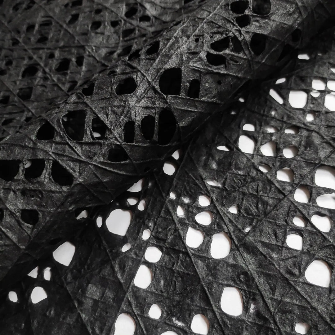 Black handmade mulberry paper featuring an intricate fishnet design created with cotton threads over kozo pulp, crafted by Kozo Studio for art and decor projects.