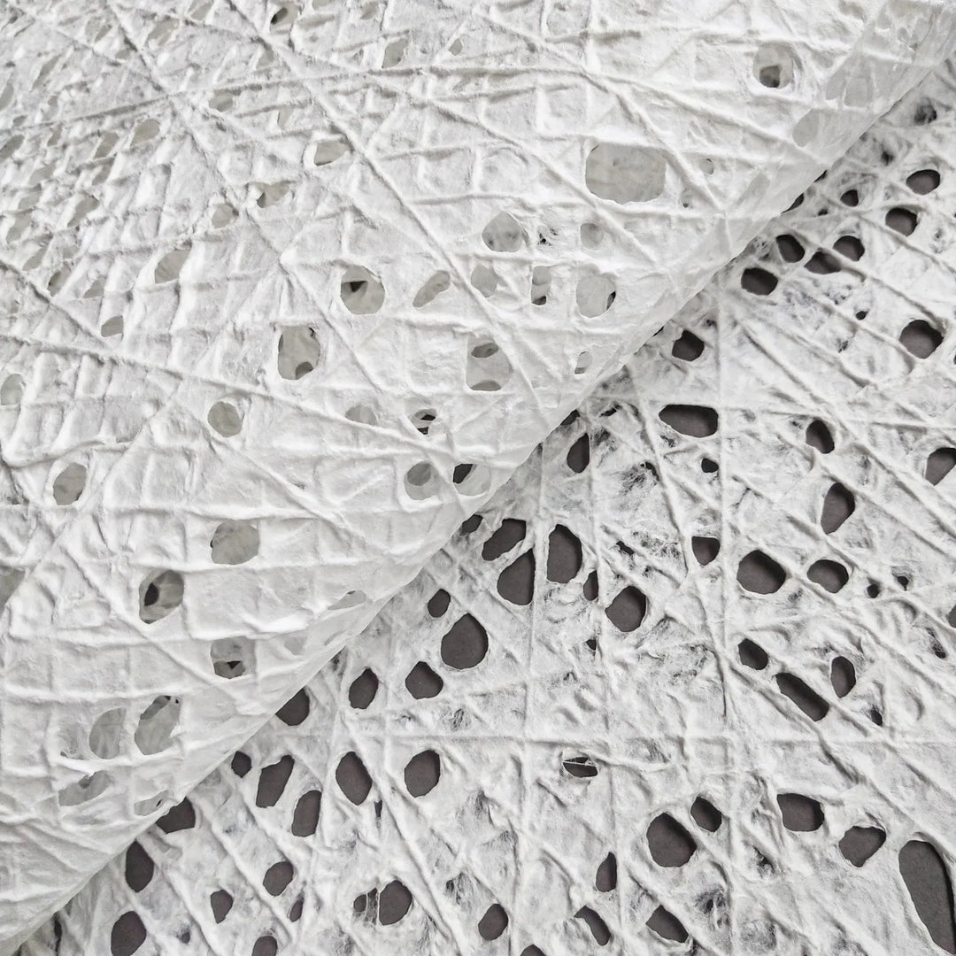 Close-up of white handmade fishnet mulberry paper from Kozo Studio, showcasing intricate cotton thread patterns over kozo pulp.