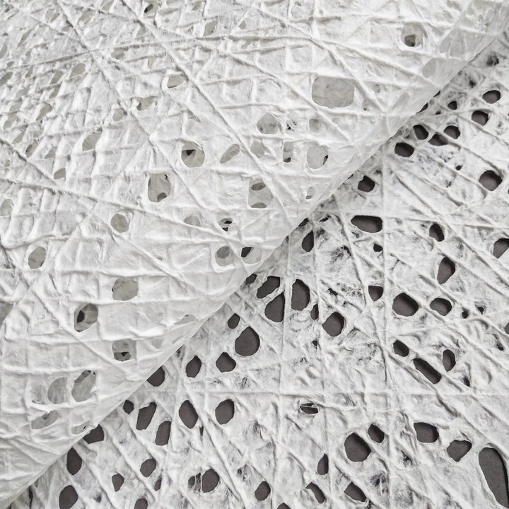 Close-up of white handmade fishnet mulberry paper from Kozo Studio, showcasing intricate cotton thread patterns over kozo pulp.