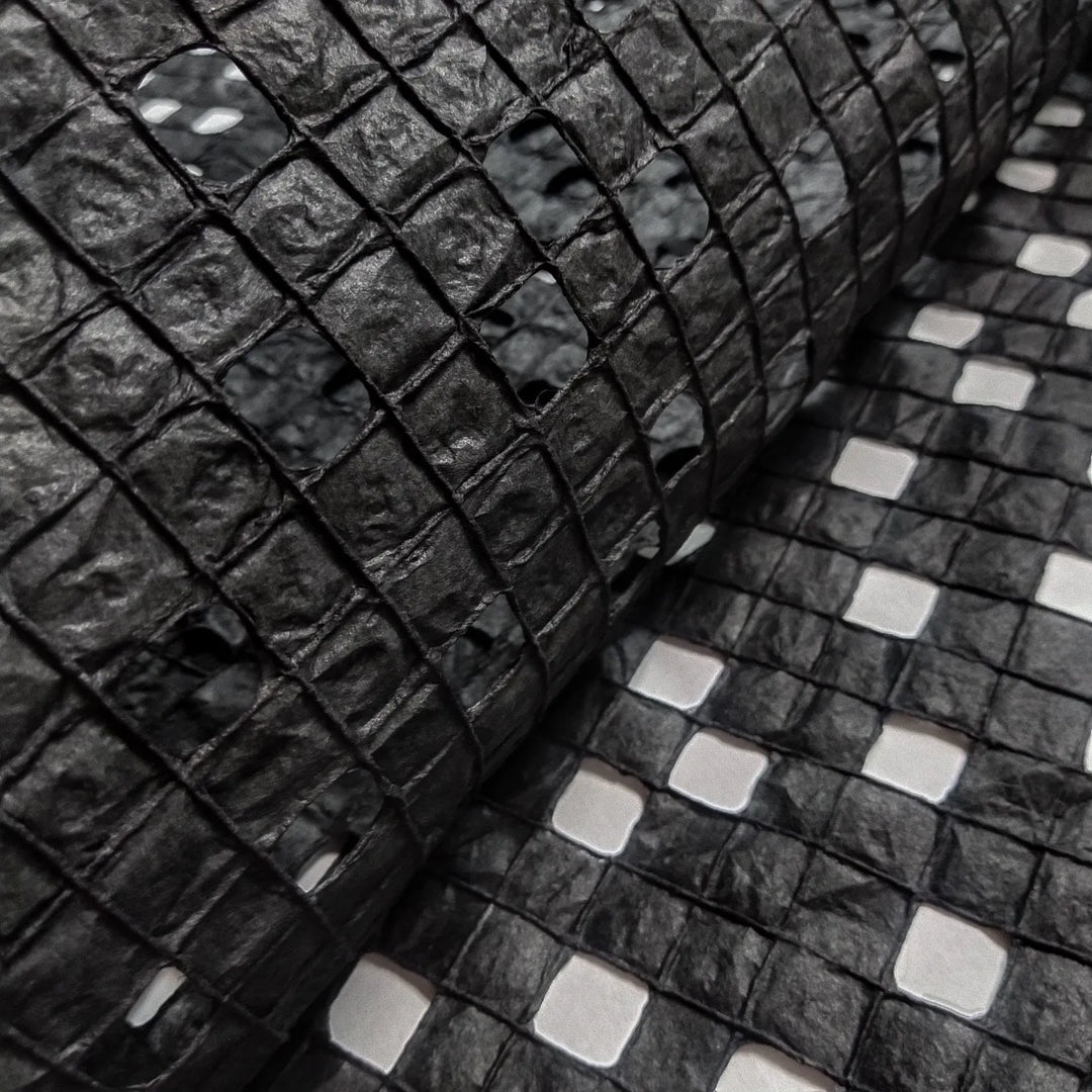 Sheet of black handmade mulberry paper from Kozo Studio, designed with meticulous cotton threading for a refined checkered effect.