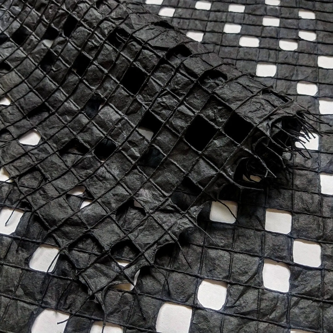 Black handmade paper from Kozo Studio featuring a delicate grid pattern made with cotton threads on mulberry paper.