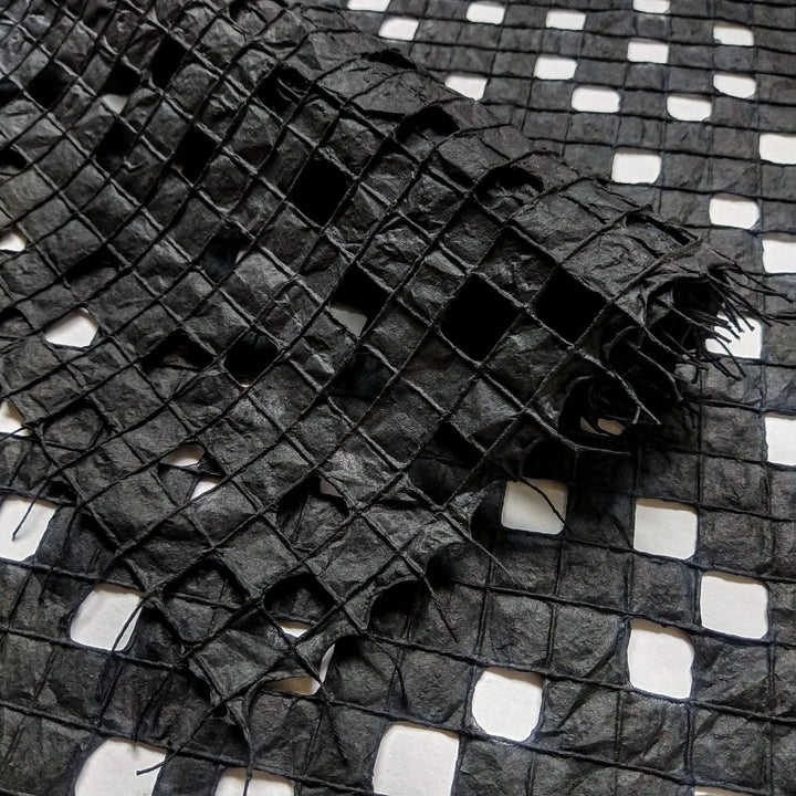 Black handmade paper from Kozo Studio featuring a delicate grid pattern made with cotton threads on mulberry paper.