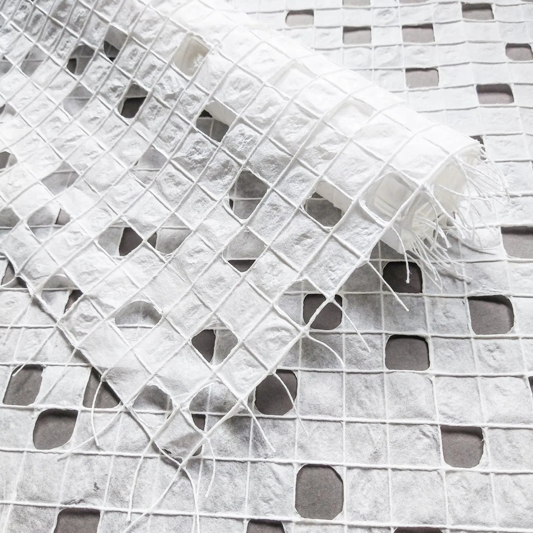 White handmade paper crafted from mulberry pulp at Kozo Studio, featuring a delicate checkered pattern formed by hand-drawn cotton threads.
