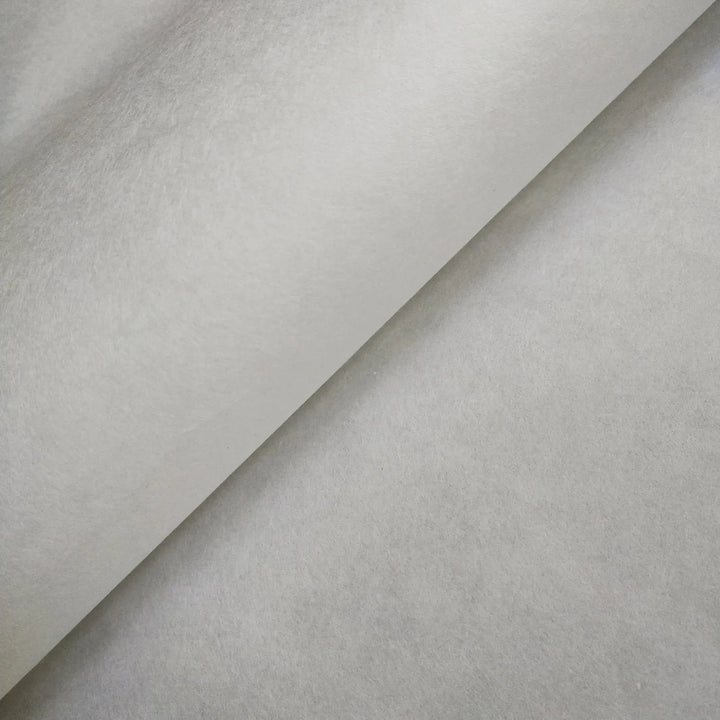 An angled close-up of a single sheet of White Kozo Paper (70 gsm, 64x94 cm) by Kozo Studio shows its smooth, subtly reflective surface with shadows highlighting the unique texture.
