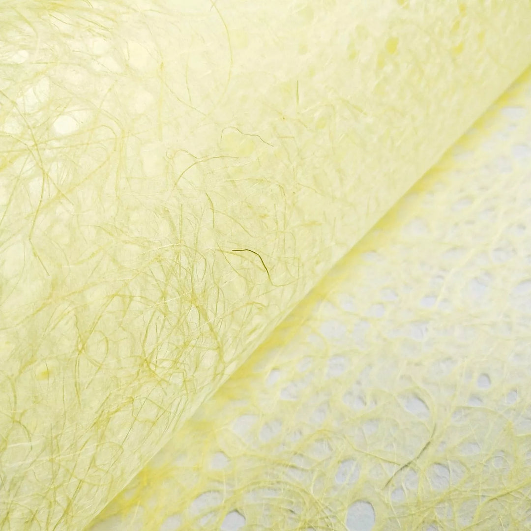 Close-up of yellow handmade paper by Kozo Studio with visible fibrous texture, highlighting the delicate lace pattern and translucent quality typical of fine mulberry paper.