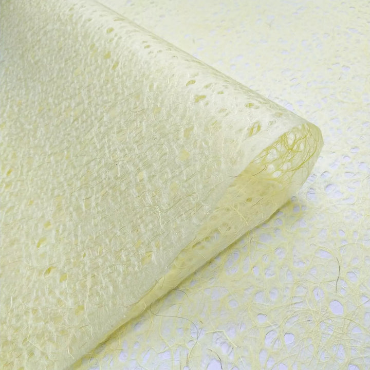 Curved sheet of yellow Kozo Studio mulberry paper, emphasizing the natural fibers and lightweight texture of premium handmade lace paper.