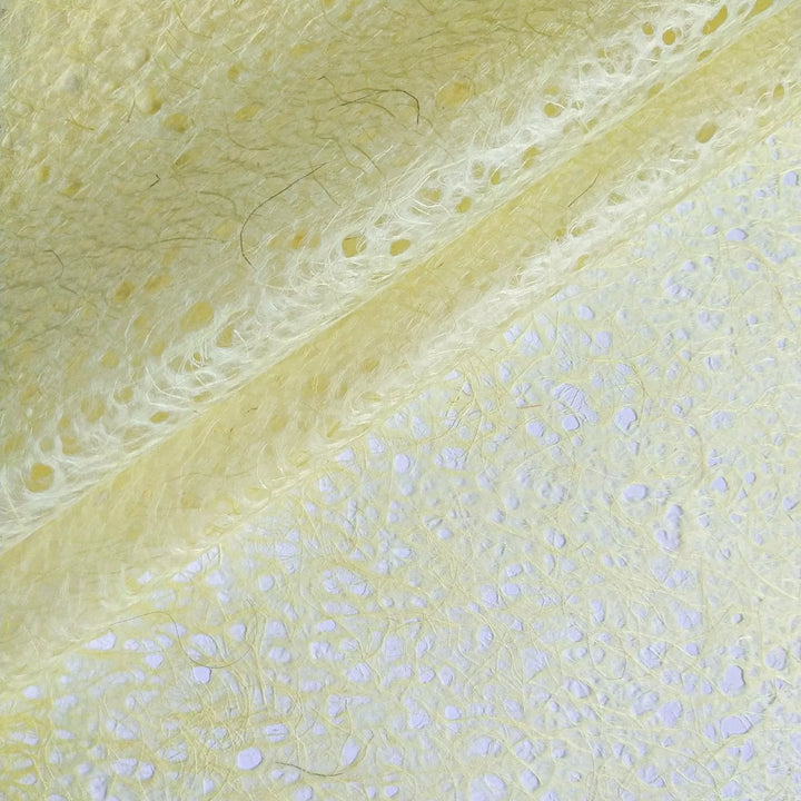 Macro shot of handmade mulberry paper by Kozo Studio, rolled to display its soft translucency and fibrous surface with delicate organic lace details.