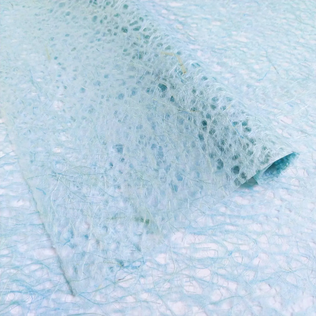 Artistic texture of Kozo Studio Asarakusui handmade paper in a light blue shade, capturing the fibrous elegance of mulberry paper.