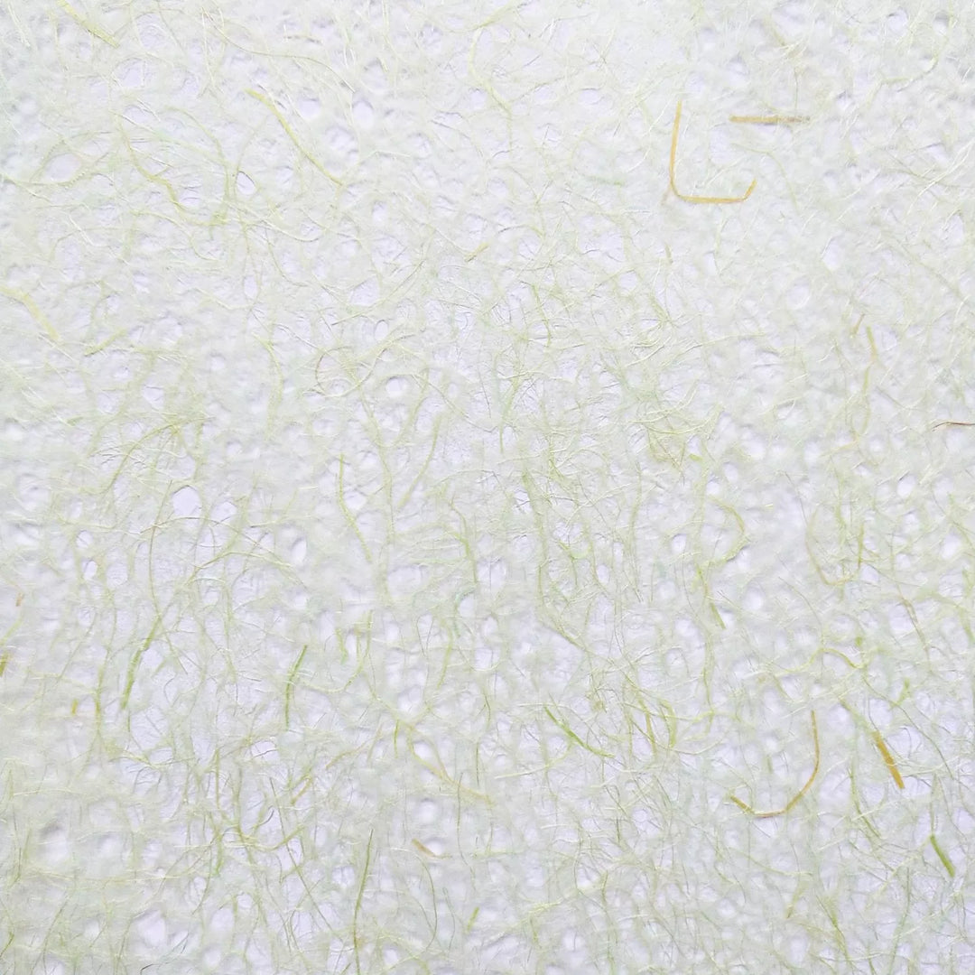 Close-up of Asarakusui Lace Paper by Kozo Studio, showcasing a textured surface reminiscent of rice paper, with subtle, random patterns of thin, wispy light green fibers interwoven throughout for a delicate and airy appearance.