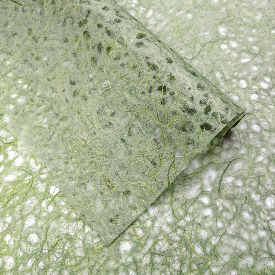 Zoomed view of green handmade mulberry paper from Kozo Studio with visible fibrous structure and lace-like Asarakusui design.
