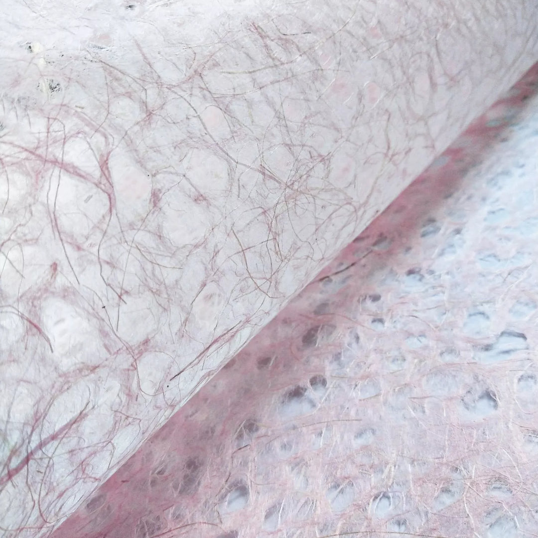 Close-up of pink Asarakusui Lace Paper from Kozo Studio showcasing handmade mulberry paper with fibrous translucent texture and organic brown threads.