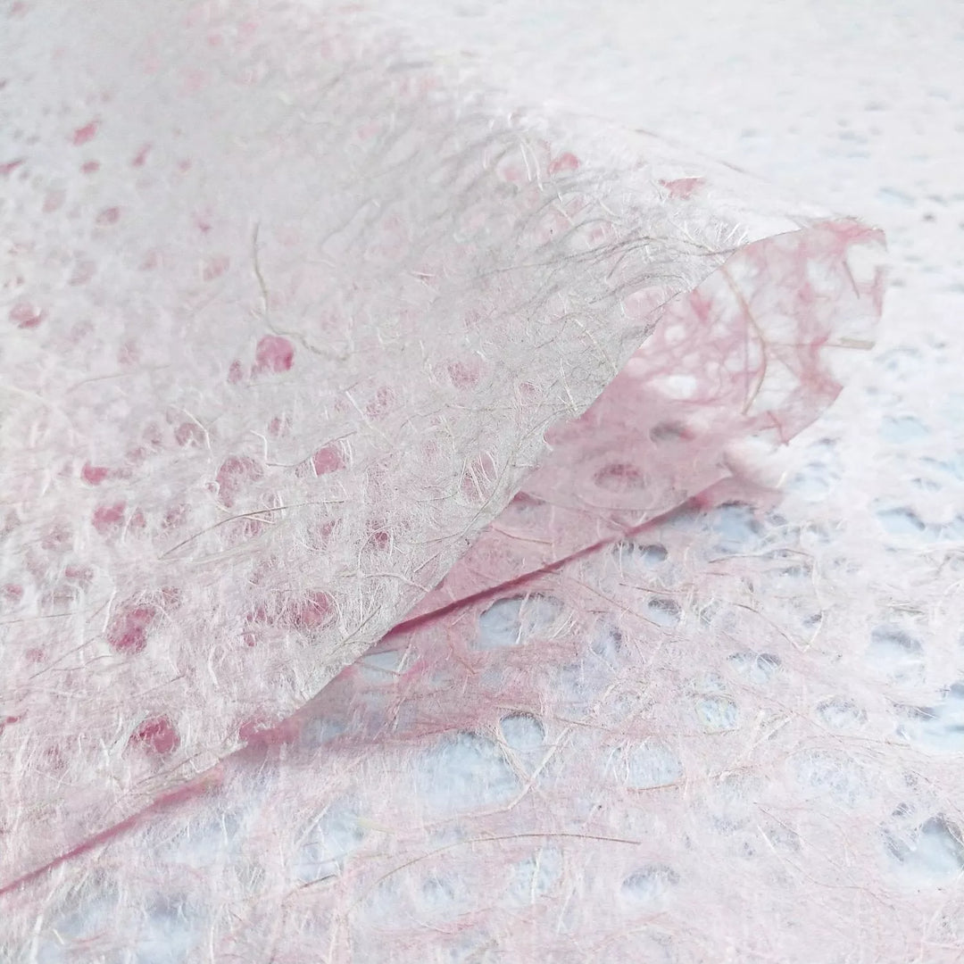 Kozo Studio mulberry paper close-up showing handmade Asarakusui Lace texture with pink and brown fiber threads for an organic aesthetic.